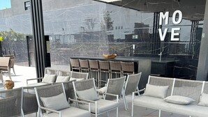 An outdoor seating area with wicker chairs and a bar. - Melhores Flats (João Pessoa)