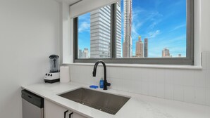 Una cocina moderna con un ventanal grande, un lavamanos empotrado y un lavavajillas.