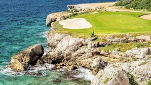 Ein Küsten-Golfplatz mit freiem Blick auf den Ozean, felsigem Gelände und einem gepflegten Grün.