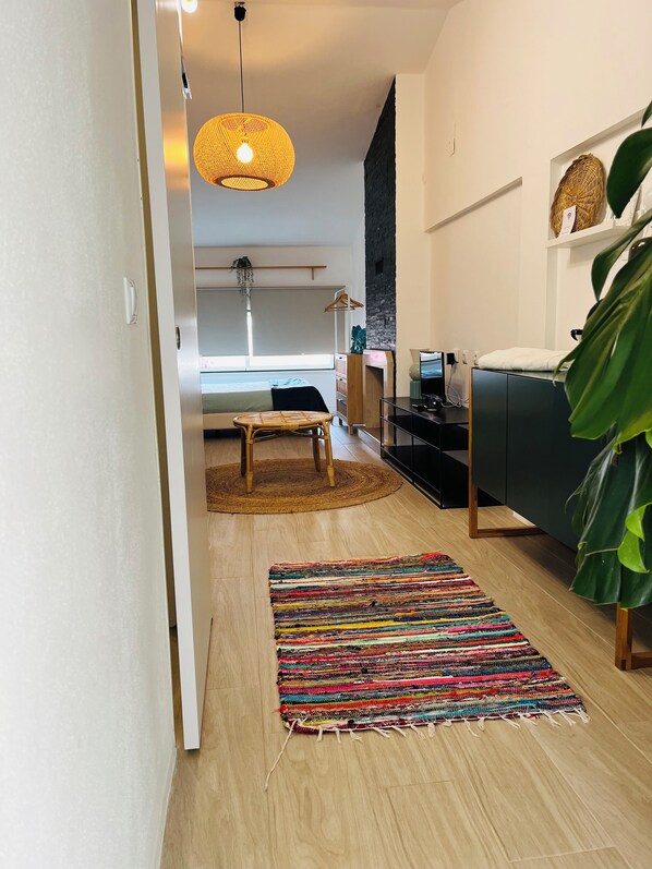 A modern living room with a sofa, a coffee table, a TV, and a large plant.