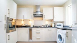 A modern kitchen with white cabinets, stainless steel appliances, and a built-in washing machine.