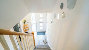 A staircase leading to a room with a door, a wooden handrail, and a small rug on the floor.