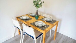 A dining table set with white plates, silverware, and wine glasses, accompanied by a vase with green foliage.