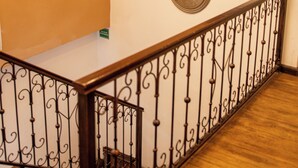 A staircase with a wrought iron railing, a wall-mounted clock, and a chandelier. - Hotel SB Cuenca (Cuenca)