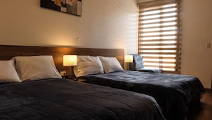 A hotel room with two beds, each with a headboard, bedside lamps, and a window with blinds. - Hotel SB Cuenca (Cuenca)