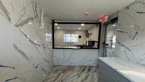 A modern interior with marble walls and a marble-patterned floor, a reception desk, and a visible window with a view outside. - Essence Express Elizabeth EWR Airport (Elizabeth)