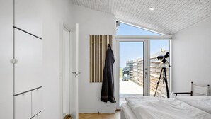 Ein modernes Schlafzimmer mit einem großen Bett, einem Teleskop und Blick ins Freie.