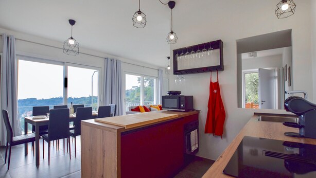 Een moderne keuken met een houten keukeneiland, een eetgedeelte met uitzicht, en een groot raam.