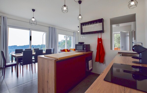 Une cuisine moderne avec un îlot central en bois, un coin repas offrant une vue agréable et une grande fenêtre.