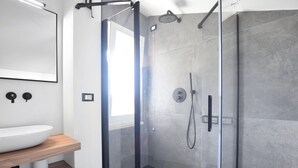 Een moderne badkamer met een douchekabinet van glas, een houten wastafelmeubel en een grote spiegel.