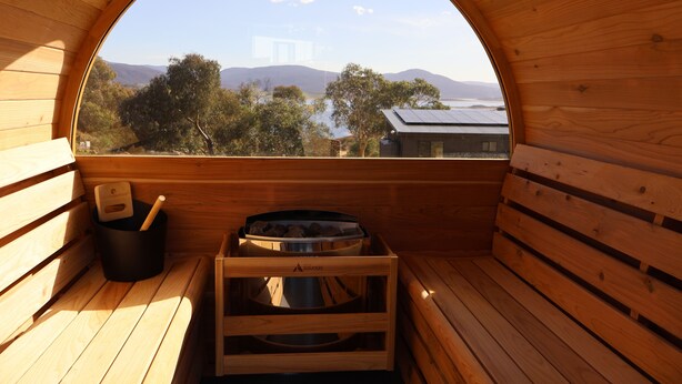 Un sauna en bois offrant une vue sur les arbres et les montagnes.