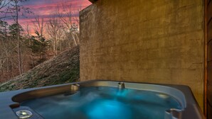 Ein Whirlpool mit Bedienfeld, vor einer Kulisse aus Bäumen und einem Sonnenuntergang.