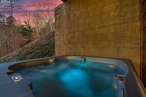 A hot tub with a control panel, set against a backdrop of trees and a sunset.