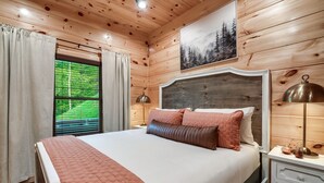Ein Schlafzimmer mit Holzwänden, einem Bett, Vorhängen, einem Fenster, einem Nachttisch und einer Lampe.