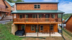 Eine zweistöckige Blockhütte mit Balkon, überdachter Veranda und einem kleinen Anbau-Garage.