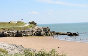 A beach with rocky cliffs, a flag, and a clear sky. - Beautiful home in Royan with WiFi (Royan)