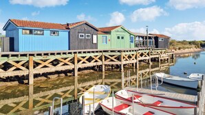 Une jetée en bois, bordée de bâtiments en bois aux couleurs vives et où sont amarrés des bateaux à son extrémité.