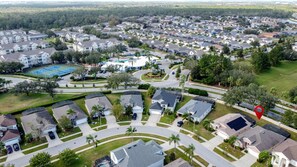 An aerial view of a residential area with houses, a tennis court, and a swimming pool.