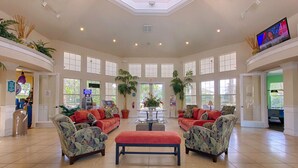 A spacious lobby with a high ceiling, large windows, and a central seating area with sofas and a coffee table. - Tranquility Palms Four Bedrooms in Windsor Palms Resort - Steps to Disney (Kissimmee)