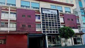 Un hôtel avec une enseigne indiquant « HÔTEL Leôn » et une pancarte « OUVERT » bien visible à l’entrée.