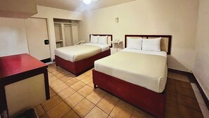 Une chambre d’hôtel avec deux lits, un bureau et un ventilateur de plafond.