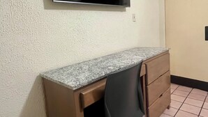 Une petite pièce comprenant un bureau, une chaise et un téléviseur fixé au mur.