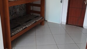 Ein Zimmer mit Etagenbett, einem gemusterten Wandbild, Fliesenboden und einer Tür.