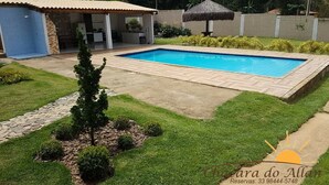 Ein rechteckiger Pool mit gefliestem Sonnendeck, umgeben von gepflegtem Rasen und einer Steingrenze.