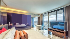 Habitación de hotel moderna con una cama grande, televisión, bañera y vistas de la ciudad.