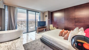 Un hotel moderno con una cama grande, una bañera, un televisor y vistas a la ciudad.