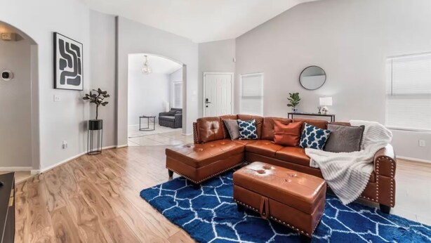 A spacious living room with a brown leather sectional sofa, a blue rug, and a ceiling fan. - Cozy 3 bedrooms, Sleeps 8 people.4605 Possum Berry Ln. North Las Vegas NVD.89081 (North Las Vegas)