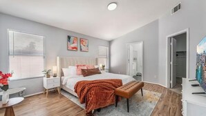 A modern bedroom with a large bed, a bedside table, a bench, and a TV. - Cozy 3 bedrooms, Sleeps 8 people.4605 Possum Berry Ln. North Las Vegas NVD.89081 (North Las Vegas)