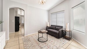 A modern living room with a sofa, a coffee table, and a chandelier. - Cozy 3 bedrooms, Sleeps 8 people.4605 Possum Berry Ln. North Las Vegas NVD.89081 (North Las Vegas)