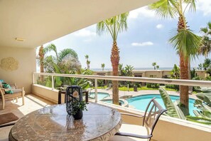 A balcony with a glass railing, a round marble table, and a potted plant. - Luxury condo with beach access (Playas de Rosarito)