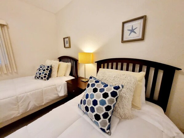 A hotel room with two single beds, a nightstand with a lamp, and a framed star decoration on the wall. - Luxury condo with beach access (Playas de Rosarito)