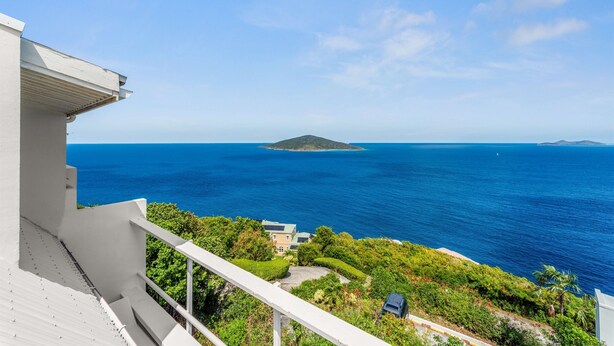 A coastal view with a balcony overlooking the sea, a small island in the distance, and lush greenery. - Generator! Top Floor Condo - 5 mins to Magens (St. Thomas)