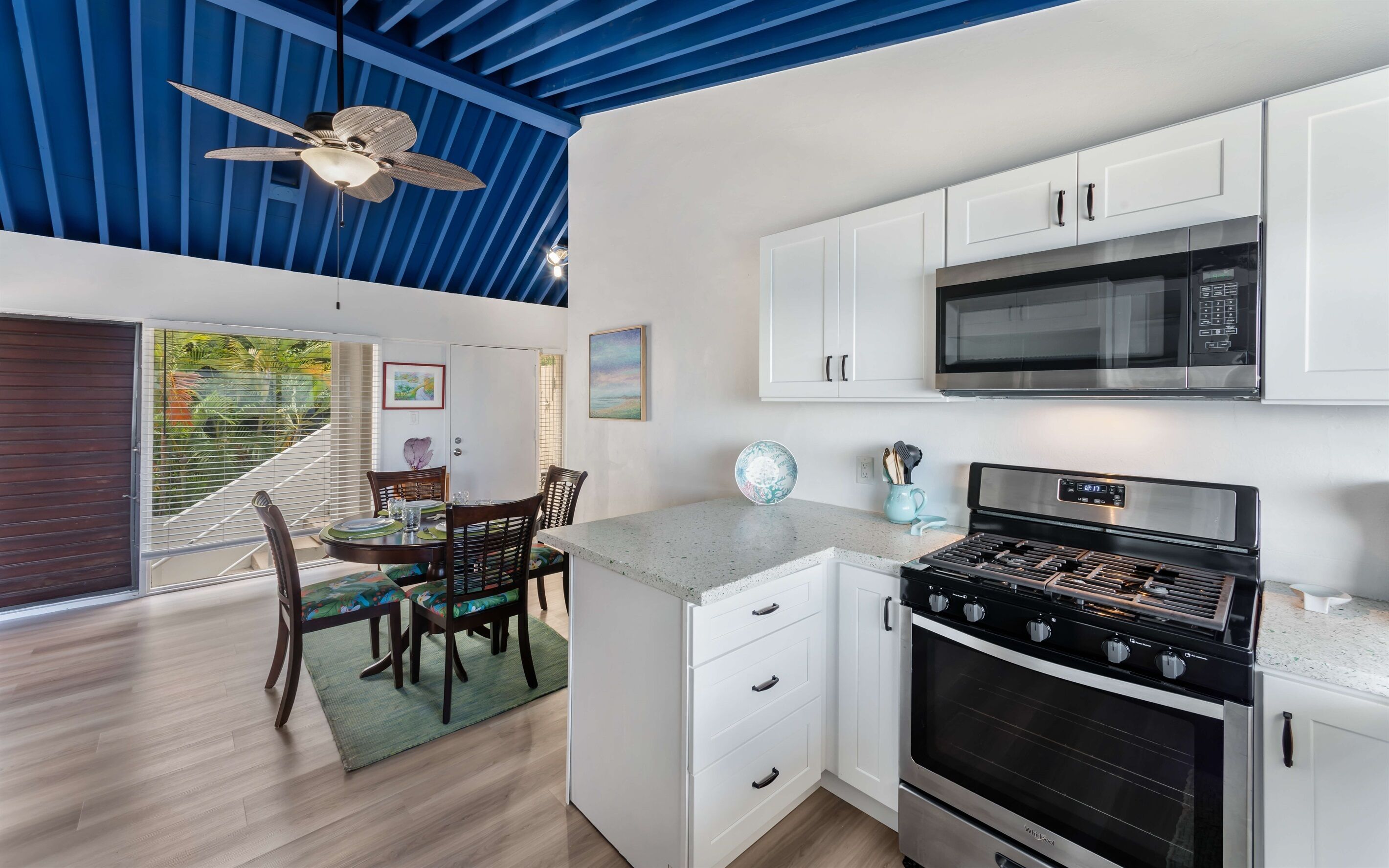A modern kitchen with white cabinets, a stainless steel stove, and a microwave.
