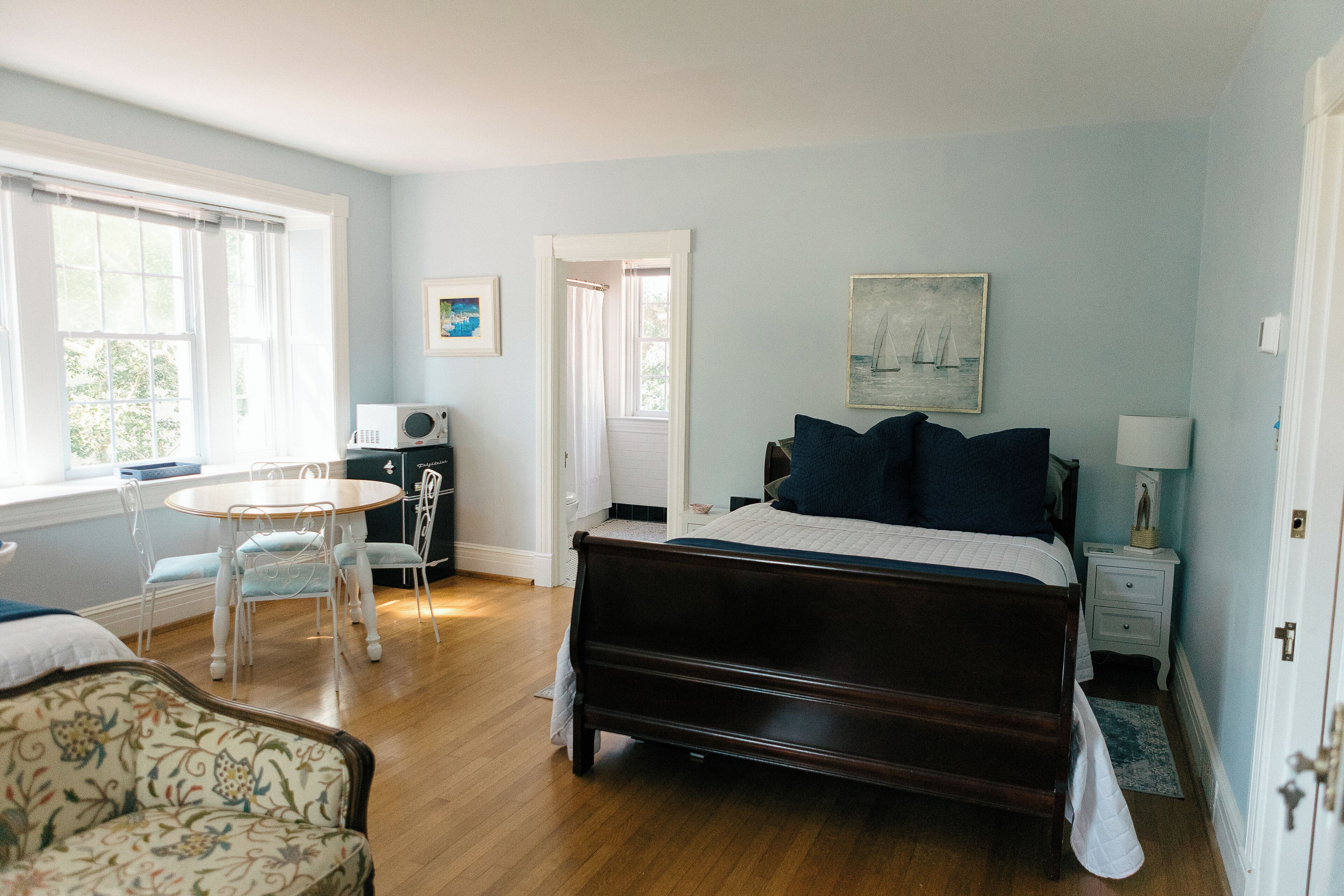 Un dormitorio con una cama, una silla, una mesa y una lámpara.