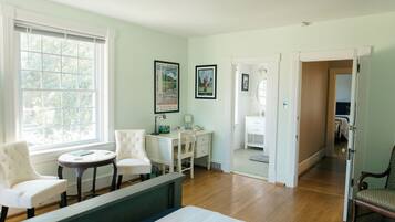 A bedroom with a bed, two chairs, a desk, and a window.