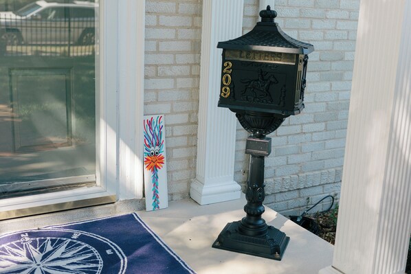 A black lantern with the number 209 on a white brick wall.