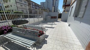 Un espace extérieur carrelé, agrémenté de bancs et de jardinières.
