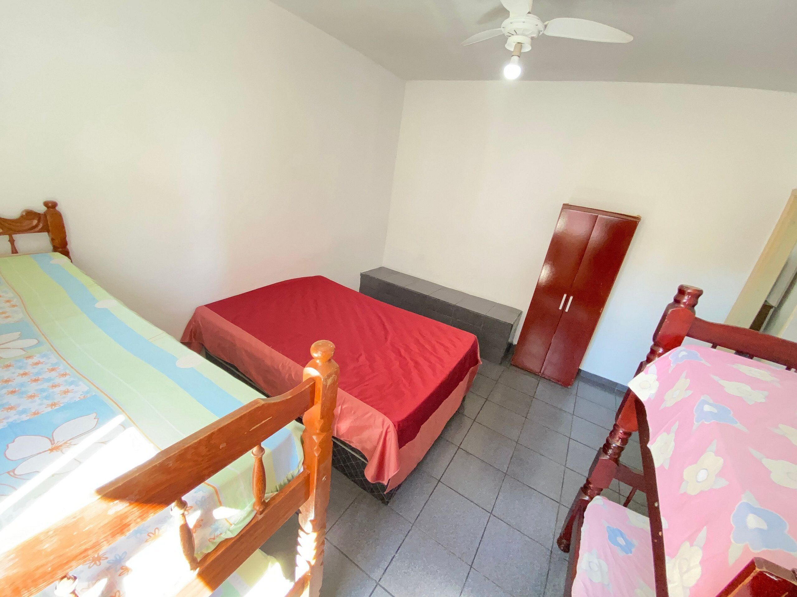 Quarto com cama, guarda-roupa, cadeira e mesa.
