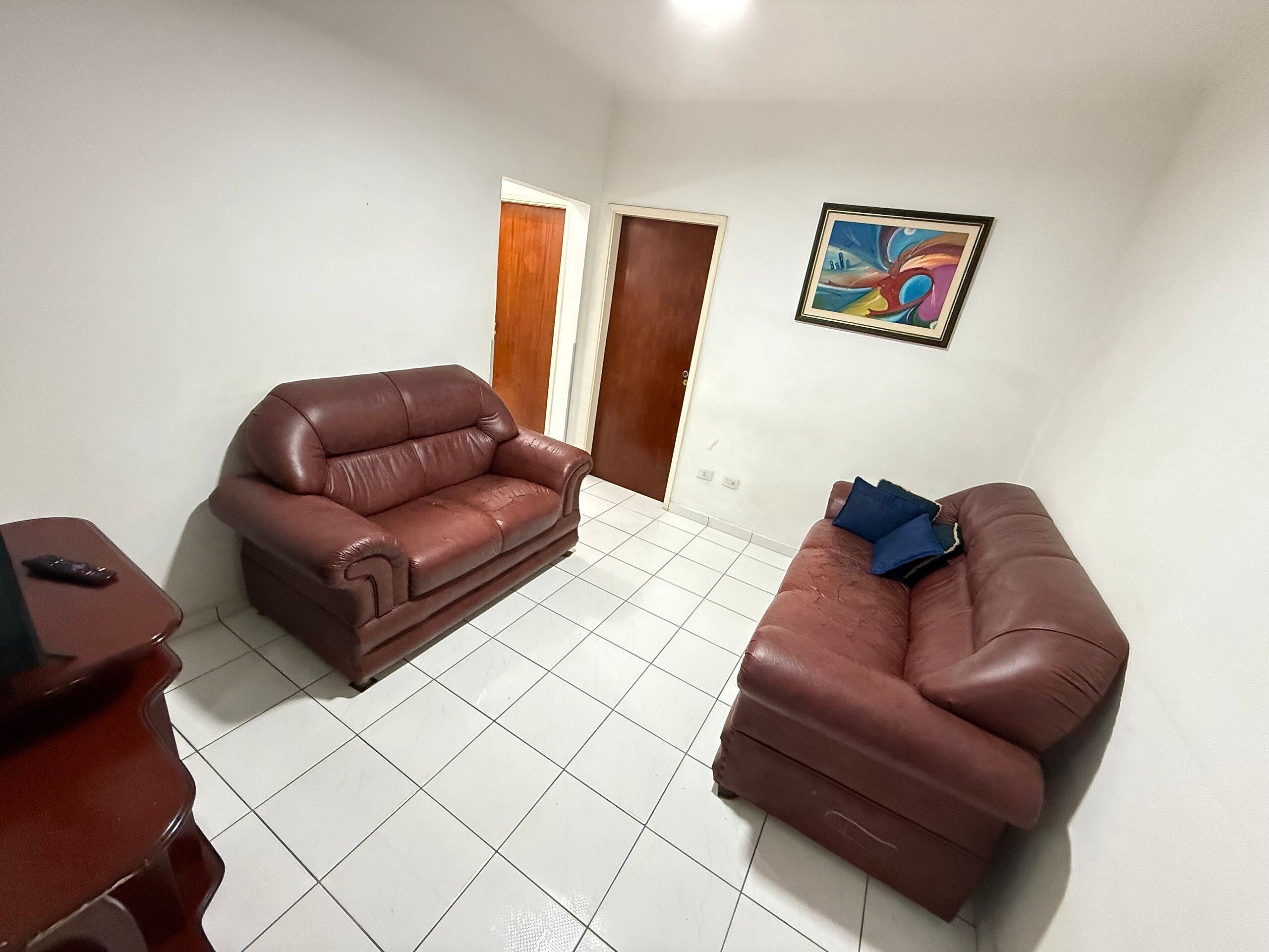 A living room with two brown leather sofas, a small table, and a colorful painting on the wall.