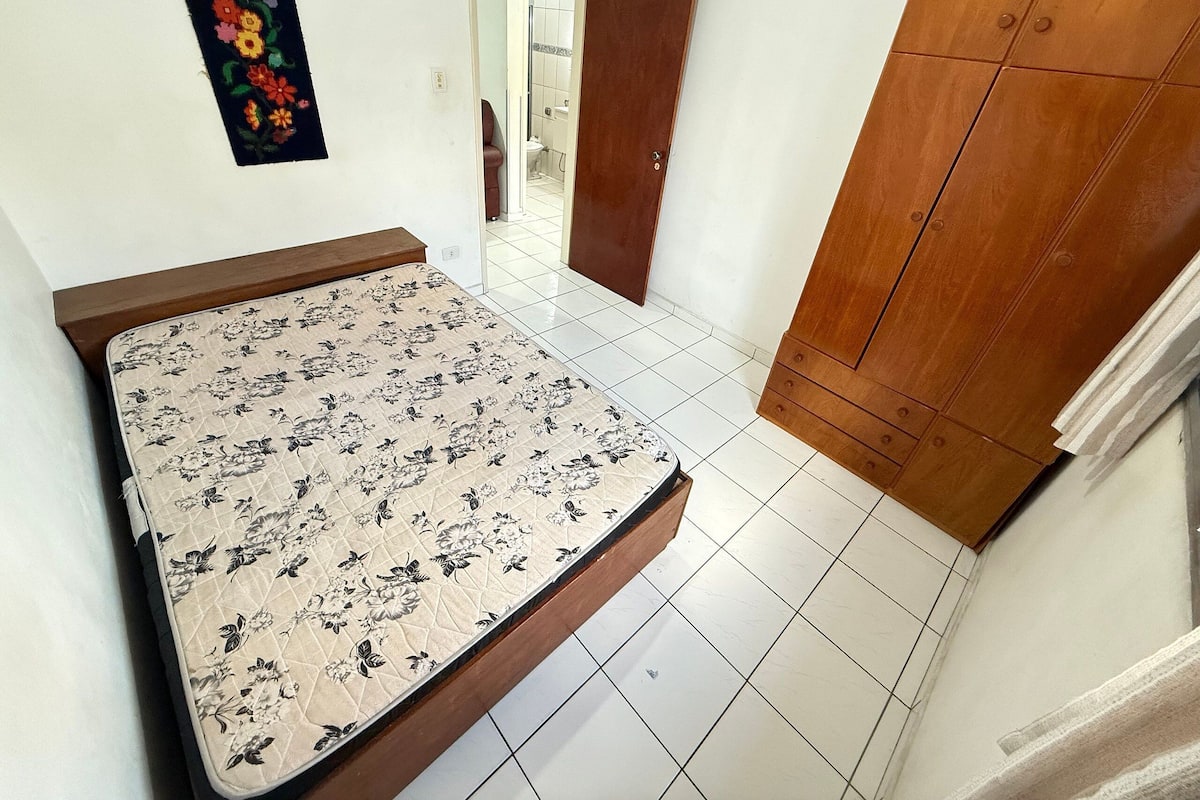 Un dormitorio con cama, un armario de madera y una puerta que da a un baño.