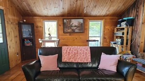 A cozy cabin interior with a leather sofa, a small table, and a bookshelf.
