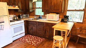 A kitchen with wooden cabinets, a stove, a microwave, and a sink.