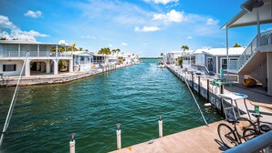 A marina with boats docked, a clear sky, and a calm waterway. - Canal Front Retreat w/ Ocean Views, 35' Dock & Golf Cart Option (Cudjoe Key)