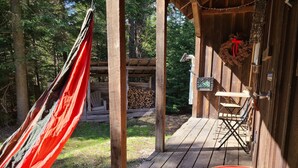 A wooden deck with a hammock, a folding chair, and a colorful rug.