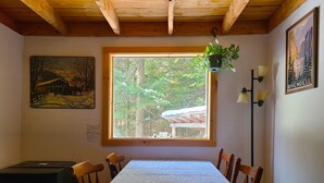 A dining area with a table set for four, a hanging plant, a painting, and a lamp.