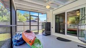A spacious room with a large sliding glass door leading to a backyard. Inside, there are kayaks and a hammock. - Charming 3-bedroom house with Heated pool/3 mins Sister Spring (Crystal River)